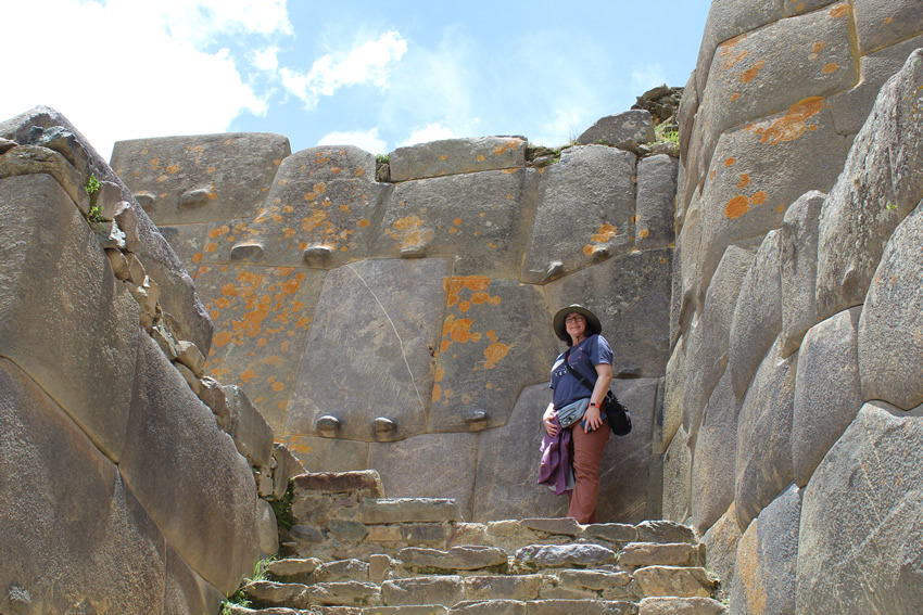 Woman standing at top of stairs in front of a megalithic wall